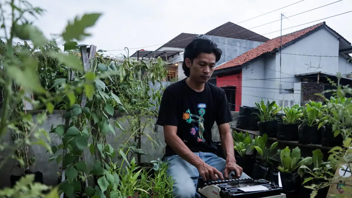 Beri Hanna sedang menulis puisi dengan mesin ketik di taman rumahnya. (M Ihsan/Radar Solo)