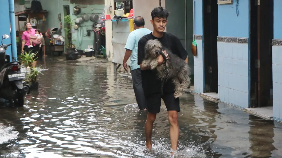 PASRAH: Warga Laweyan yang jadi korban banjir mengevakuasi anjing peliharaannya ke tempat aman. (ARIEF BUDIMAN/RADAR SOLO)