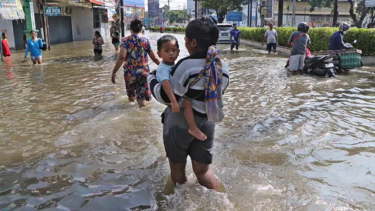 Warga berjalan di tengah banjir di wilayah Joyotakan, Solo, Rabu (15/4/2026). (ARIEF BUDIMAN/RADAR SOLO)
