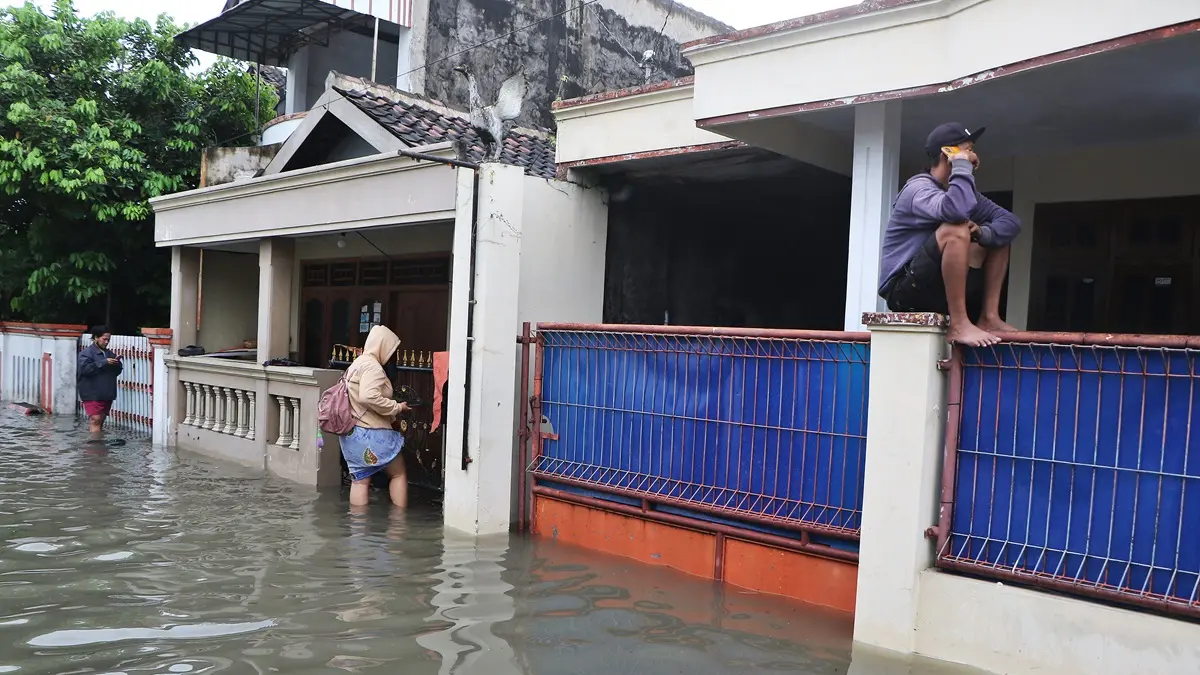 Warga Desa Sanggrahan, Grogol, Sukoharjo duduk termangu di atas pagar rumahnya yang tergenang banjir, Rabu (15/4). (ARIEF BUDIMAN/RADAR SOLO) 