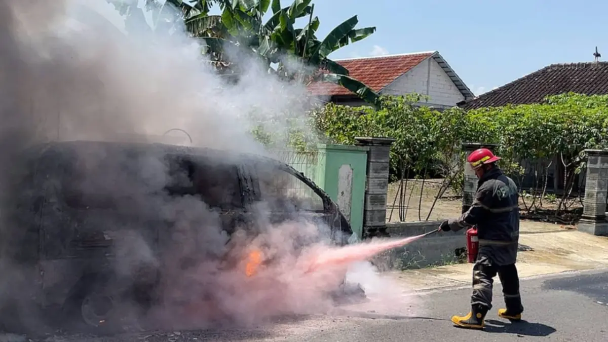 Petugas damkar mencoba memadamkan mobil Daihatsu Espass yang terbakar di Kampung Jatimalang RT 01 RW 01, Desa Kateguhan, Tawangsari, Sukoharjo, Rabu siang (15/4). (IWAN KAWUL/RADAR SOLO)