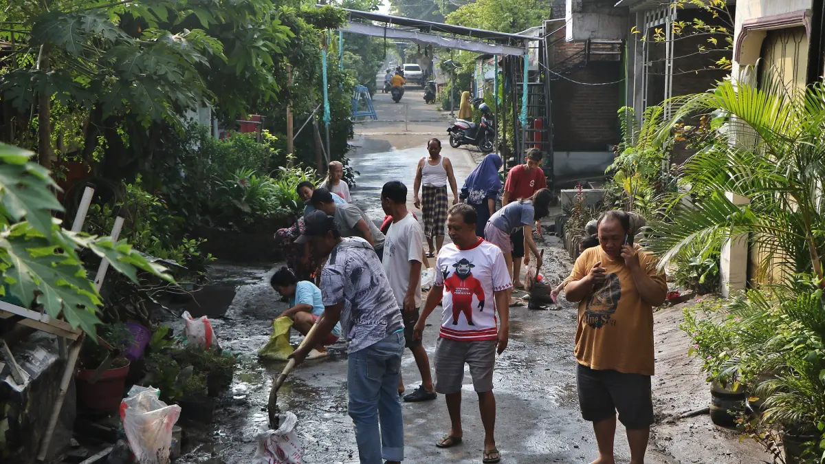 Warga Joyotakan Solo membersihkan lumpur sisa-sisa banjir, Kamis (16/4/2026). (Arief Budiman/Radar Solo)