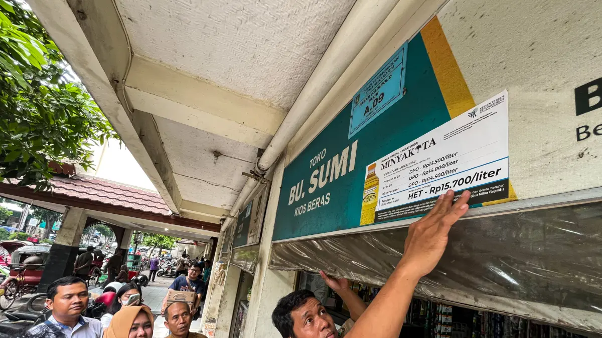 Petugas Dinas Perdagangan (Disdag) Kota Solo memasang stiker pemberitahuan harga eceran tertinggi (HET) MinyaKita di Pasar Kadipolo, Laweyan, Senin (11/5). (M IHSAN/RADAR SOLO)