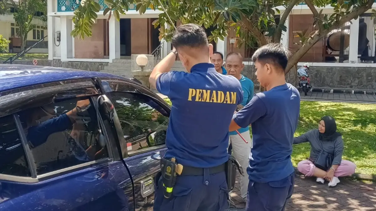 Personel Damkar Boyolali berupaya membuka pintu mobil yang terkunci otomatis sedangkan kuncinya masih berada di dalam kabin, Minggu (17/5/2026). (ABDUL KHOFID/RADAR SOLO)