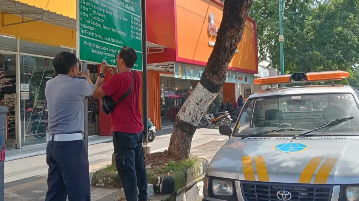 Petugas Dishub Sragen pasang papan tarif parkir di salah satu jalan Kota Sragen. (Ahmad Khairudin/Radar Solo)