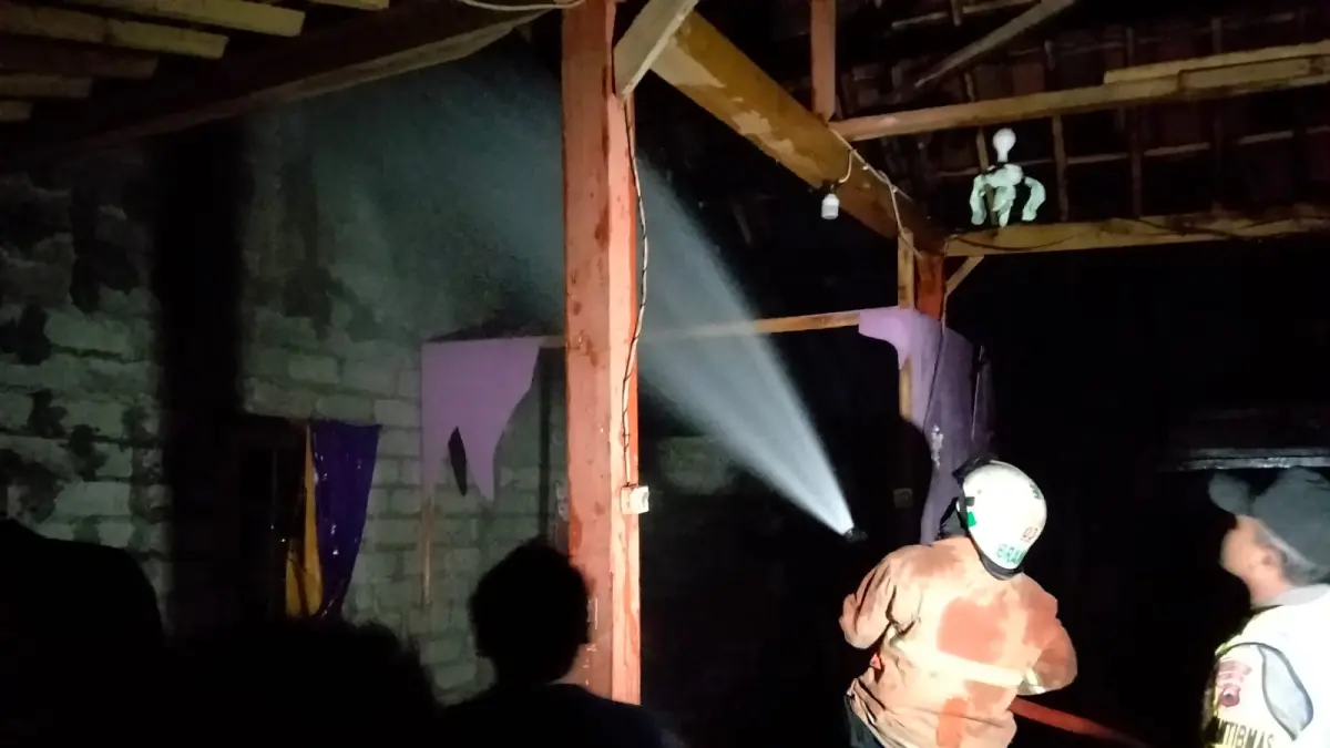 Personel Damkar Sragen padamkan api yang membakar rumah Mbah Painem di Dukuh Telon RT 39, Desa Sambi, Kecamatan Sambirejo, Kabupaten Sragen, Jumat (19/6/2026) malam. (DOK.DAMKAR SRAGEN) 