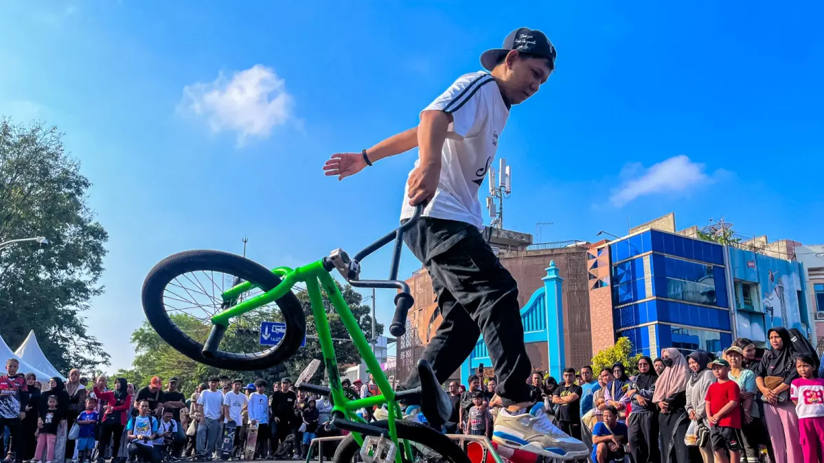 MEMUKAU: Seorang rider BMX menunjukkan skill luar biasa dengan melakukan atraksi keseimbangan di momen CFD Solo, Jalan Slamet Riyadi, Minggu kemarin (21/6/2026). (M. IHSAN/RADAR SOLO) 