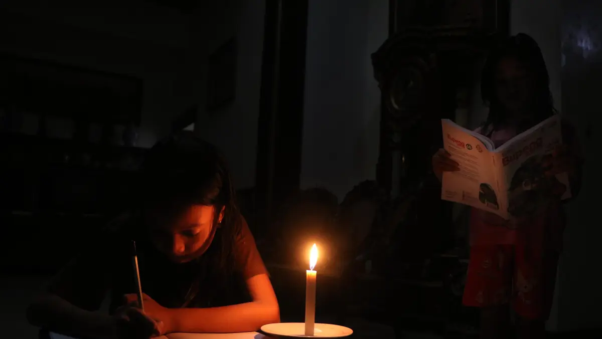 Ilustrasi seorang anak tengah membaca dengan bantuan lilin saat situasi tengah adanya kebijakan listrik mati. (Arief Budiman/Radar Solo)