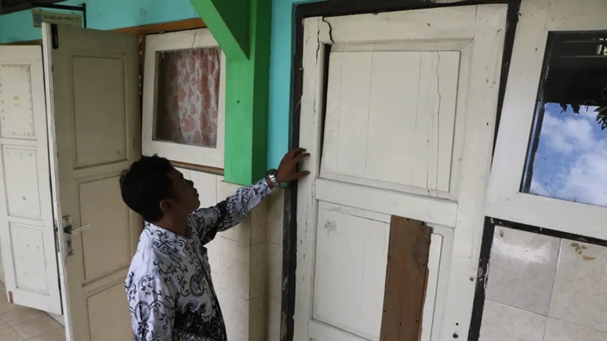 Guru memperlihatkan kondisi pintu salah satu ruang kelas yang rusak di SMPN 23 Solo, belum lama ini. (ARIEF BUDIMAN/RADAR SOLO)
