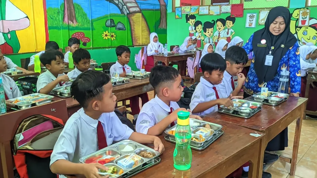 Guru SD di Wonogiri memantau para murid yang sedang menikmati menu MBG belum lama ini. (IWAN ADI/RADAR SOLO) 