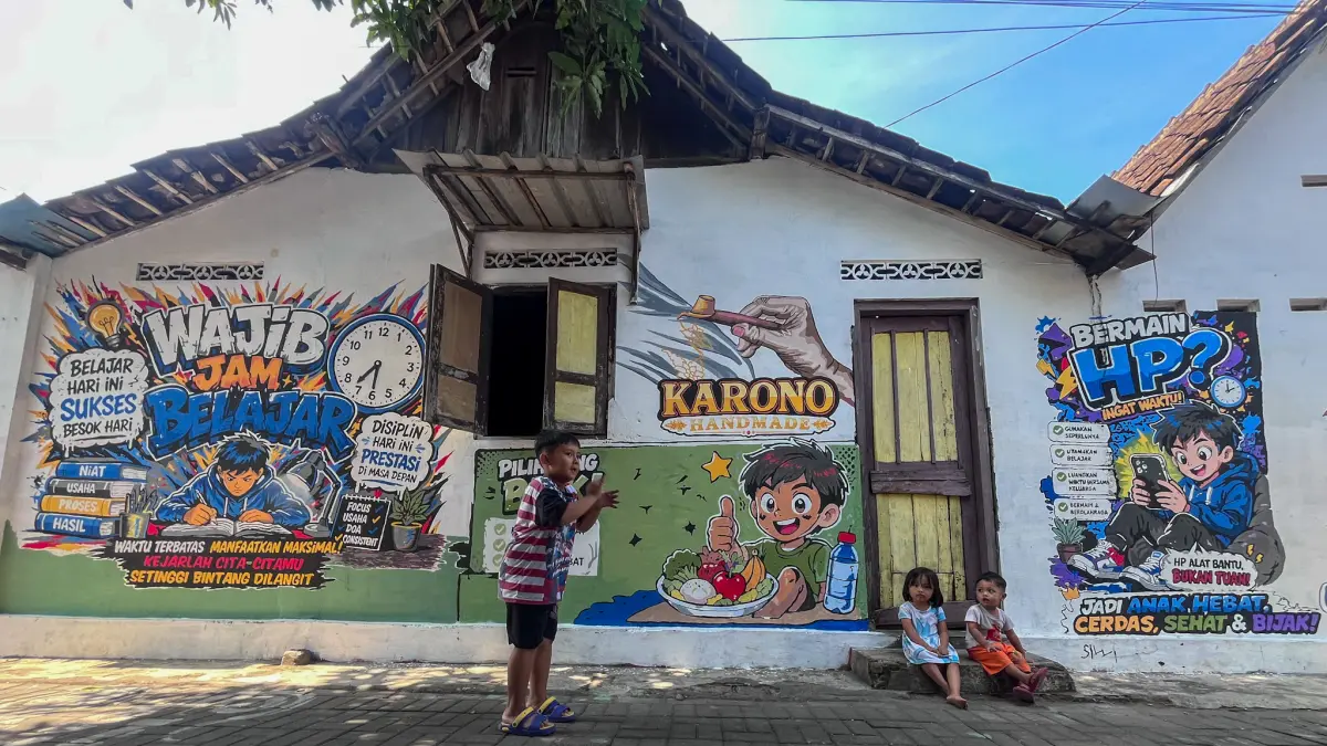 Tembok rumah warga di Kampung Mutihan RT 03 RW10, Laweyan, Solo dicat mural berisi pesan edukatif, Selasa (21/7). (M IHSAN/RADAR SOLO)