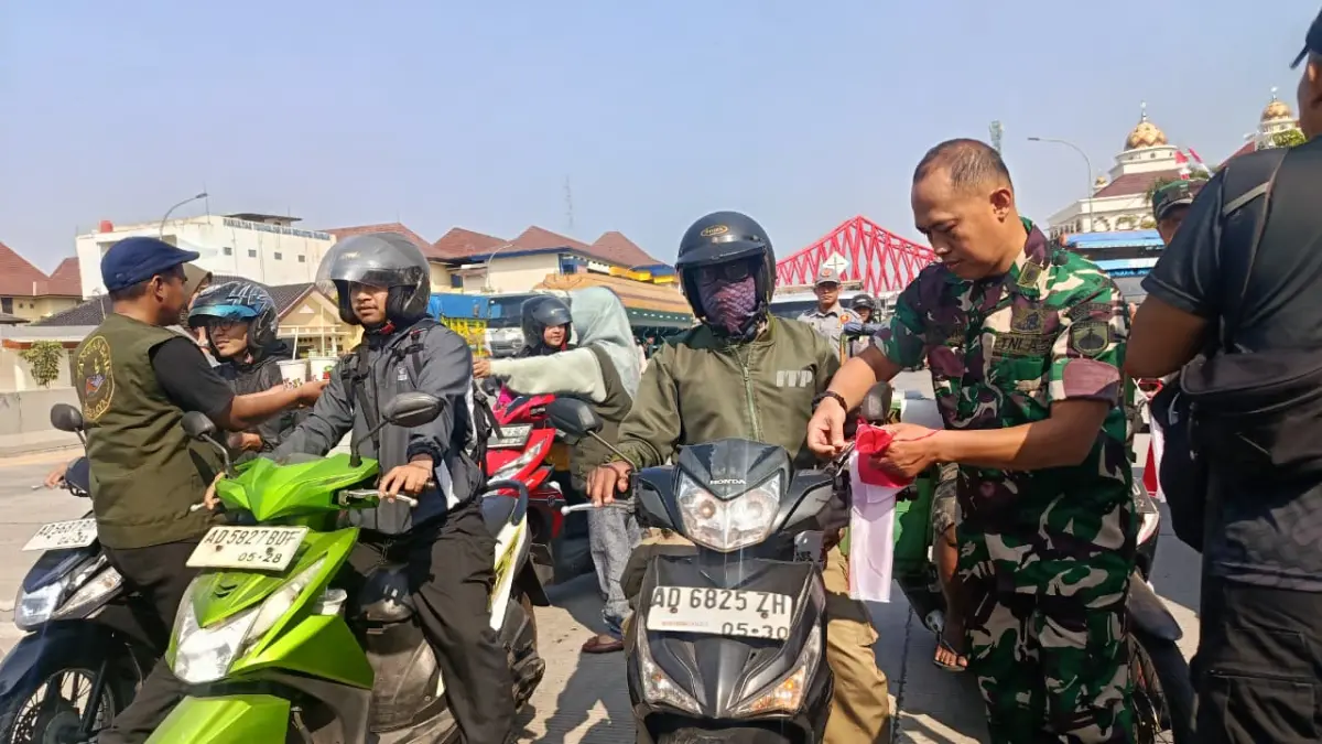 Dandim 0735/Surakarta Mayor CPL Warji bersama warga membagikan bendera merah putih kepada pengguna jalan di depan TPU Bonoloyo, Selasa (11/8). (Alfida Nurcholisah/Radar Solo)