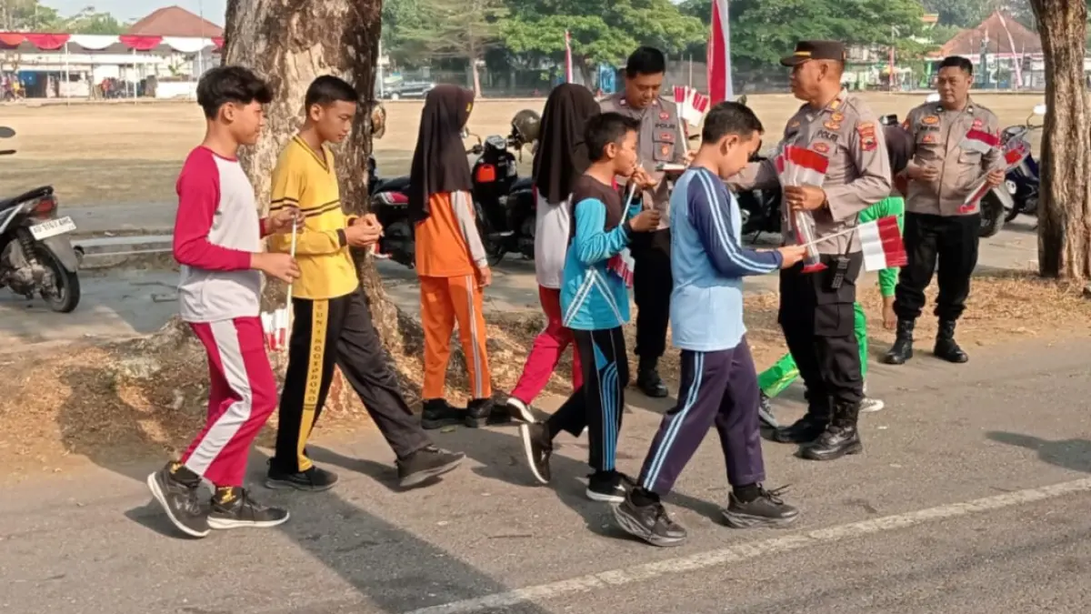 Kapolsek Gondang AKP Suparno (dua dari kanan) memimpin pembagian bendera merah putih gratis ke siswa. (Ahmad Khairudin/Radar Solo)