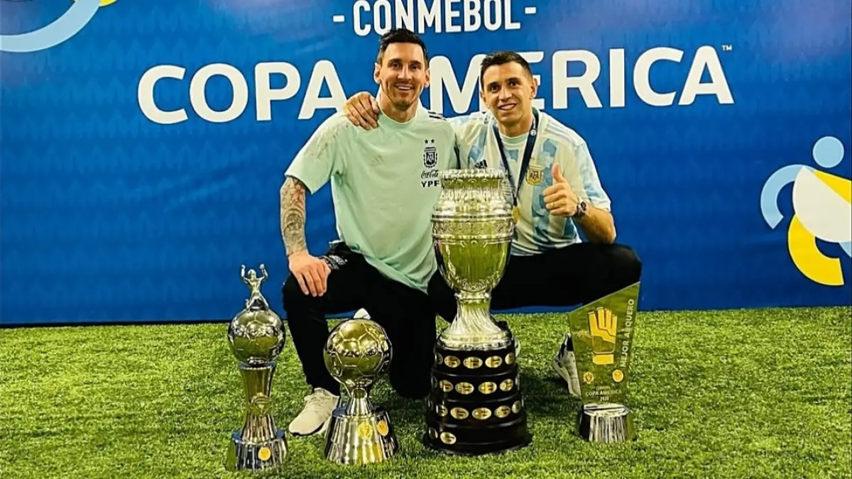 Penjaga gawang Timnas Argentina, Emiliano Martinez bersama Lionel Messi dengan berbagai piala yang diraih Timnas Argentina. (Instagram @emi_martinez26)