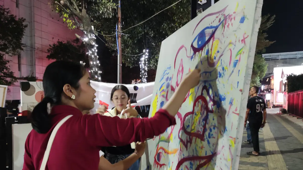 ‎ABSTRAK: Seseorang tengah membuat karya seni lukis di Koridor Gatsu, Jumat malam (11/9). (Hernindya Jalu/Radar Solo)