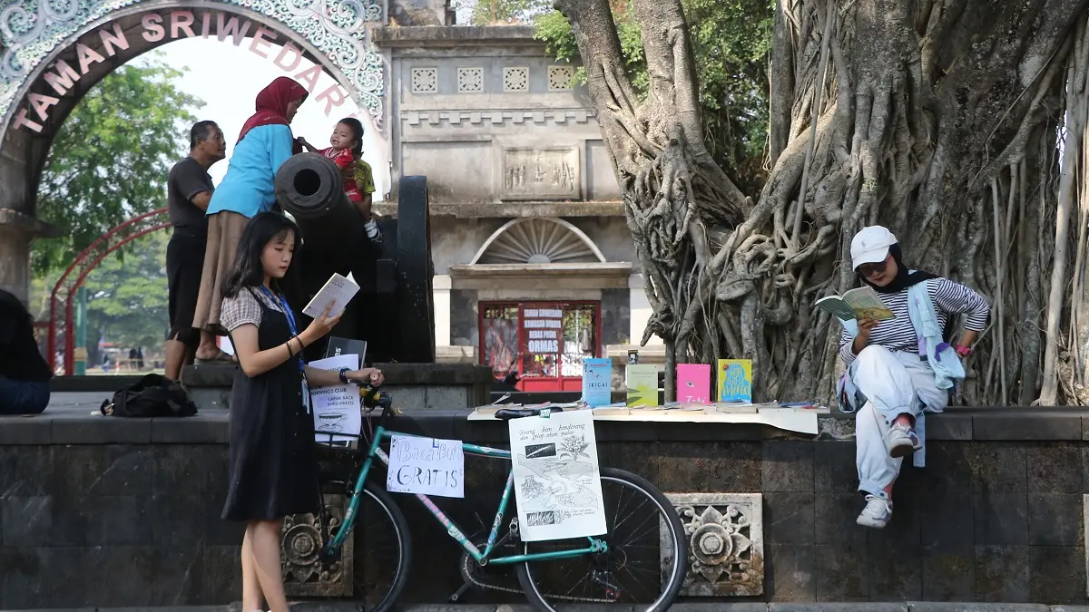 Destyn Ayu Safitri (kanan) aktif mengajak masyarakat untuk gemar membaca lewat perpustakaan sepeda. Di sini, siapa saja bisa membaca buku secara gratis. (ARIEF BUDIMAN/RADAR SOLO)