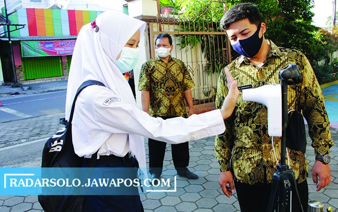 PROKES KETAT: Siswa SMPN 8 Surakarta cek suhu tubuh sebelum simulasi PTM. (M IHSAN/RADAR SOLO)