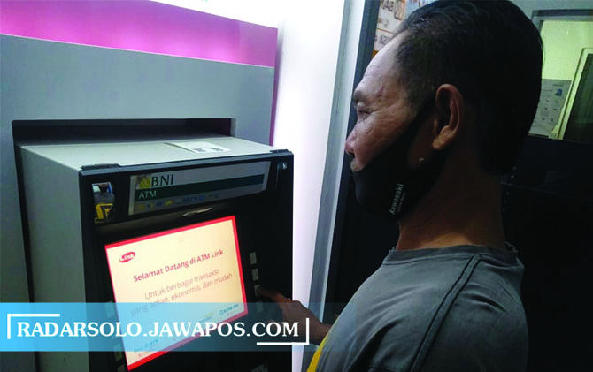POLEMIK: Salah seorang hendak mengambil uang di ATM yang ada di Sriwedari, kemarin. (NIKKO AUGLANDY/RADAR SOLO)
