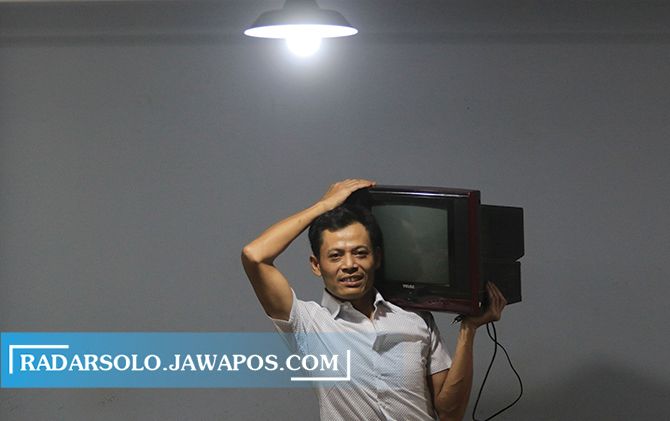 BIKIN BANGGA: Kusrin menggotong televisi tabung hasil produksinya di Wonosari, Jatikuwung, Gondangrejo, Karanganyar.