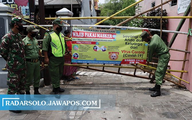 BERPERAN: Petugas linmas di Kota Surakarta saat memasang spanduk pencegahan Covid-19. (RADAR SOLO PHOTO)
