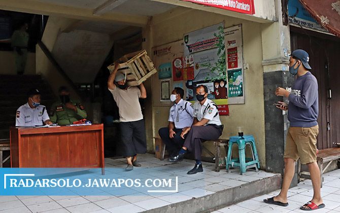 Dengan pengawasan dari petugas, pedagang mengemasi barang mereka karena Pasar Harjodaksino ditutup hingga awal November.