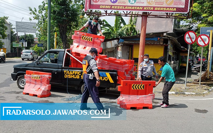UBAH KEBIJAKAN: Personel Dishub Sukoharjo hendak memasang kembali water barrier di lokasi penyekatan, Kamis (12/8). (IWAN KAWUL/RADAR SOLO)