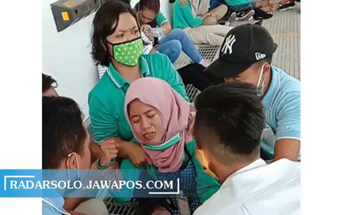 Para karyawan mencoba menenangkan karyawati yang kesurupan.