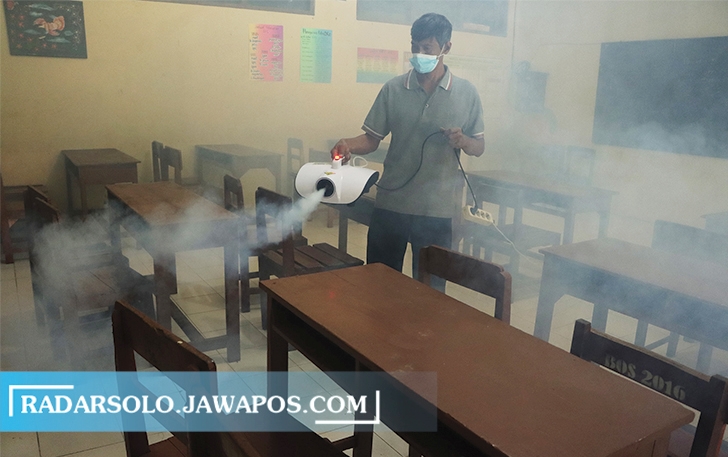 DISINFEKSI: Karyawan sterilkan ruang kelas dengan fogging di SMPN 8 Surakarta. Dana BOS Kinerja dipangkas membuat sejumlah sekolah kecewa. (M. IHSAN/RADAR SOLO)