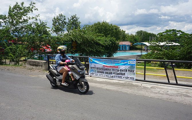 Warga melintas di depan gerbang utama Umbul Pelem, Desa Wunut, Kecamatan Tulung, Klaten yang ditutup, Senin (2/11).
