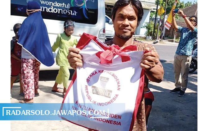 Warga menunjukkan sembako yang dibagikan rombongan Presiden Jokowi usai ziarah ke makam orang tua di  Dusun Mundu, Desa Selokaton, Kecamatan Gondangrejo, Sabtu (29/8).