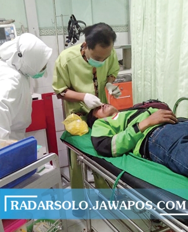 DAPAT PERAWATAN: Driver ojek online mendapat perawatan setelah kena benang layanan saat melintas di jalan. (RAGIL LISTIYO/RADAR SOLO)