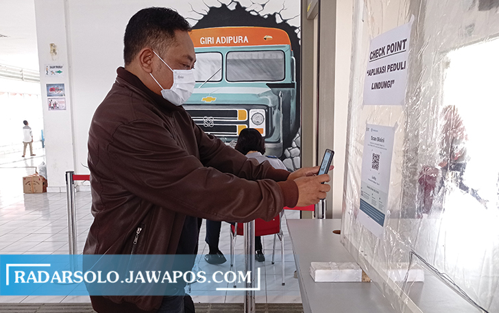 UJI COBA: Petugas memberikan petunjuk kepada penumpang sebelum memindai barcode aplikasi PeduliLindungi di Terminal Tipe A Giri Adipura Wonogiri, Senin (6/9). (IWAN ADI LUHUNG/RADAR SOLO)