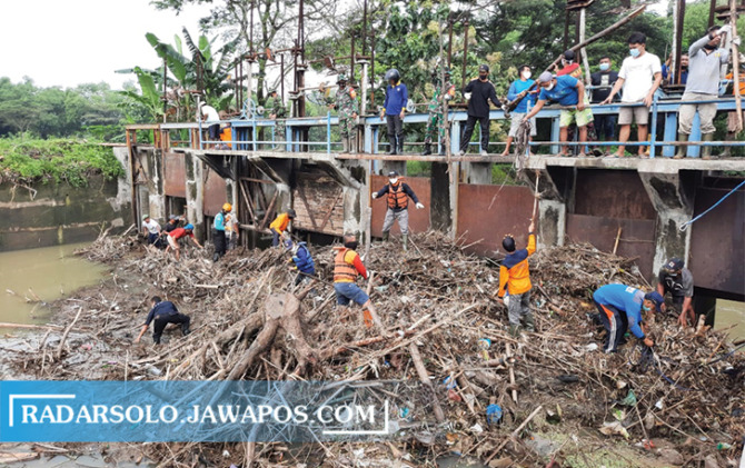 CEGAH BANJIR: Relawan gabungan membersihkan sampah dahan pohon yang menumpuk di Bendungan Siluwur, Desa Tegalsari, Kecamatan Weru, kemarin (1/10). (IWAN KAWUL/RADAR SOLO)
