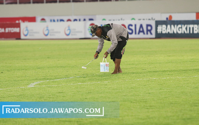LAYAK: Pekerja mengecat garis Stadion Manahan, Senin (18/10) malam. (M. IHSAN/RADAR SOLO)