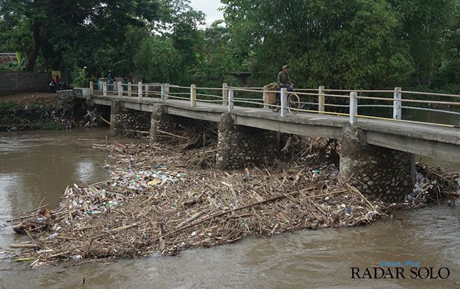 ILUSTRASI JEMBATAN AMBROL: Tumpukan sampah rumpun bambu dan volume air yang tinggi dan deras bisa membahayakan konstruksi jembatan. (RADAR SOLO PHOTO)