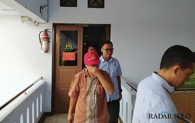 Mantan camat Karangtengah (topi merah) menutupi wajahnya saat akan dibawa ke Rutan Wonogiri