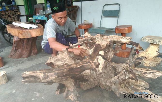 Rahardian sedang membersihkan limbah akar kayu sebelum dibuat kerajinan.