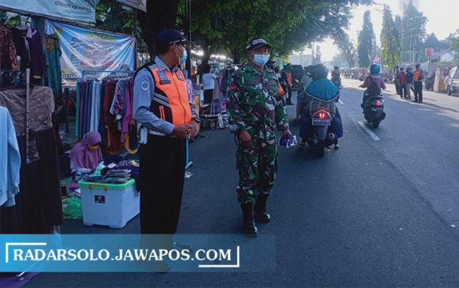 PUSAT KOTA: Petugas mengawasi kegiatan masyarakat di sekitar Alun-Alun Satya Negara yang ramai pada Minggu pagi. (IWAN KAWUL/RADAR SOLO)