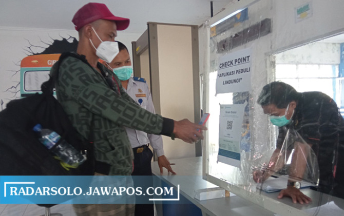 KETAT: Penumpang keberangkatan didampingi petugas terminal memindai barcode PeduliLindungi di Terminal Tipe A Giri Adipura Wonogiri, beberapa waktu yang lalu. (IWAN ADI LUHUNG/RADAR SOLO)