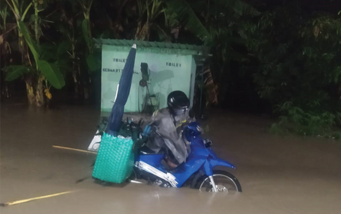 NEKAT: Pengendara motor menerjang banjir di Kecamatan Ngemplak. (ISTIMEWA)