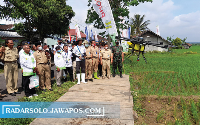 INOVASI: Sejumlah petani Desa Dayu, Karangpandan melihat penggunaaan drone sprayer untuk penyemprotan pupuk. (RUDI HARTONO/RADAR SOLO)
