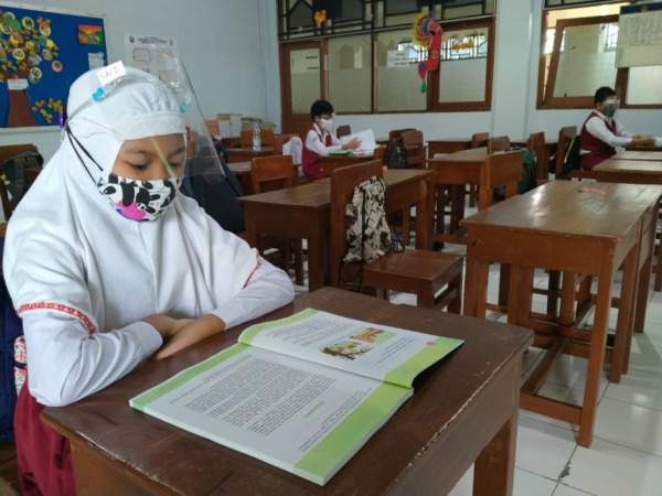 JAGA JARAK: Siswa salah satu SD Islam swasta di Kota Solo melaksanakan pembalajaran tatap muka di kelas, Senin (24/1). Khusus siswa kelas I, ortu boleh menjemput ke dalam sekolah. (ISTIMEWA)