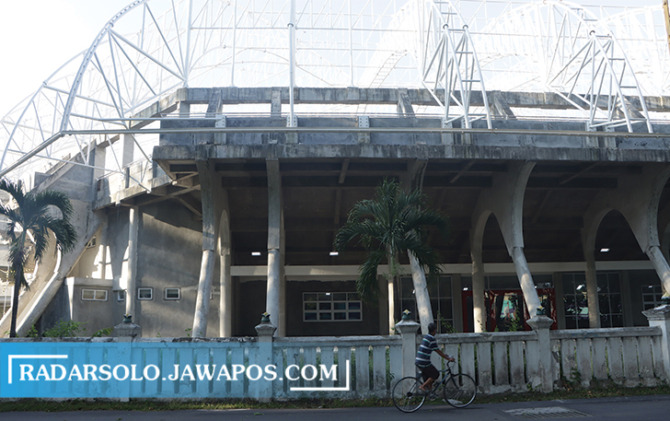 MOLOR: Warga melintas di depan proyek GOR Manahan.  (M. IHSAN/RADAR SOLO)
