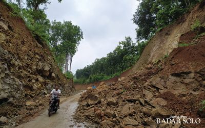 Pengendara sepeda motor melintas di antara longsoran tanah di jalan lingkar selatan (JLK) Wonogiri-Selogiri, Rabu (11/3).