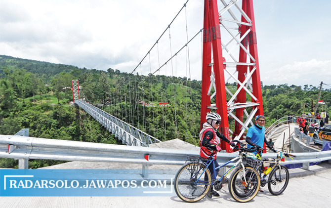 IKON WISATA BARU: Pesepeda menyempatkan diri singgah di jembatan gantung Dusun Girpasang, Desa Tegalmulyo, Kecamatan Kemalang yang baru saja diresmikan, Kamis (20/1). (M. IHSAN/RADAR SOLO)