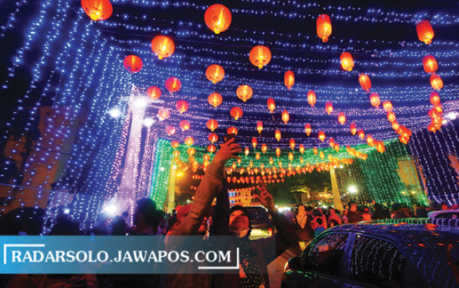 Warga menikmati lampion Imlek yang baru dihidupkan di kawasan Pasar Gede Solo, Minggu (30/1) malam. (ARIEF BUDIMAN/RADAR SOLO)