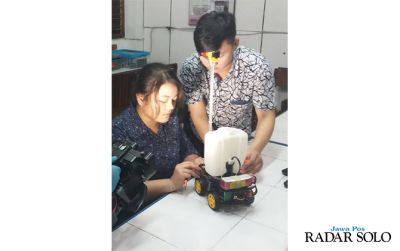 ANTIKORONA: Dua mahasiswa Teknik Elektro Unika Soegijapranata menguji Robot Elnika 19 buatannya.
