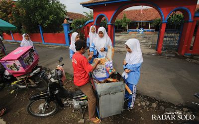 Para siswi tengah jajan di depan sekolah. Hingga kini, jumlah anak putus sekolah di Kota Solo masih tinggi. (ARIEF BUDIMAN/RADAR SOLO)