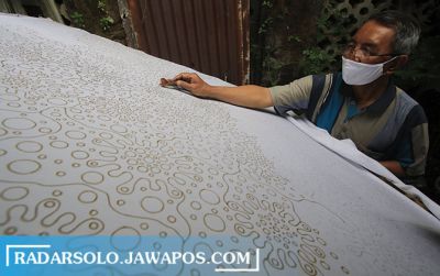 Perajin di Kampung Batik Laweyan ini menggambar pola batik di atas kain putih kemarin (19/5).