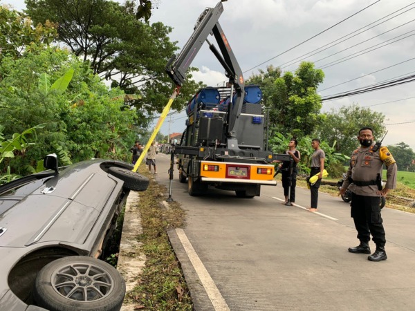 PAKAI CRANE: Personel SAR Samapta Polres Karanganyar mengevakuasi mobil yang terjun di selokan Desa Brujul, Kecamatan Jaten. (RUDI HARTONO/RADAR SOLO)